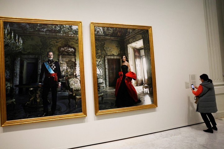 Una mujer toma una foto de una etiqueta junto a los retratos de los Reyes de España Felipe y Letizia realizados por la fotógrafa estadounidense Annie Leibovitz. REUTERS/Susana Vera 