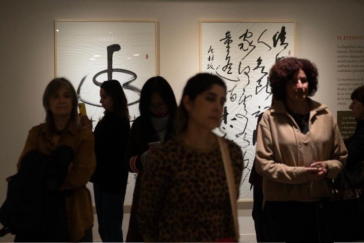 Una mujer tomando una fotografía a obras de caligrafía china exhibidas durante la muestra "Poéticas del movimiento. Arte, escritura y caligrafía en China". (Xinhua/Martín Zabala)