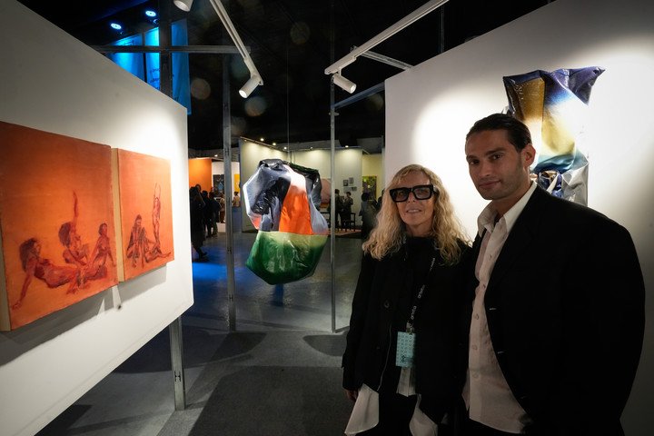 La artista y diseñadora de modas Jessica Trosman junto a sus obras con el galerista Tomás Redrado en el espacio Tomás Redrado Art, durante la inauguración de la feria arte Arteba en Buenos Aires el 27 agosto 2025. Foto: Mariana Nedelcu.