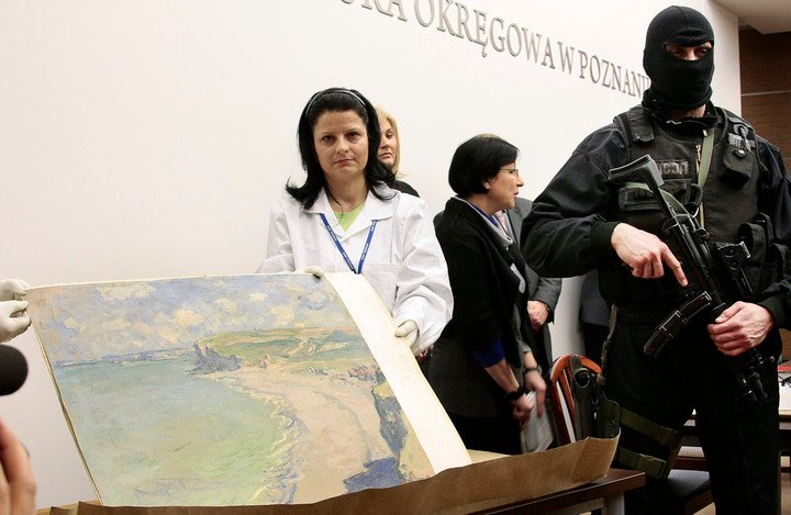 Funcionarios del Museo Nacional de Arte de Poznan sostienen una pintura del impresionista francés Claude Monet, robada hace en el 2000 y recuperada una década después.